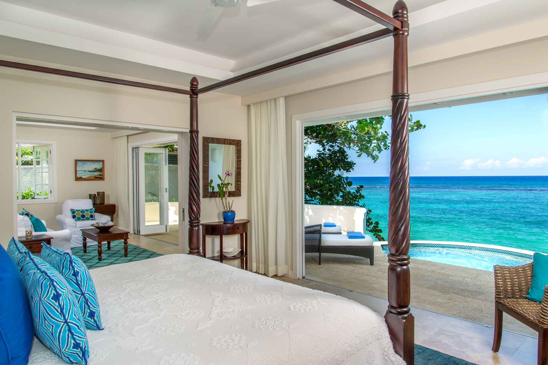 Jamaica Inn bedroom with four-poster bed and view of a private pool in front of the ocean.