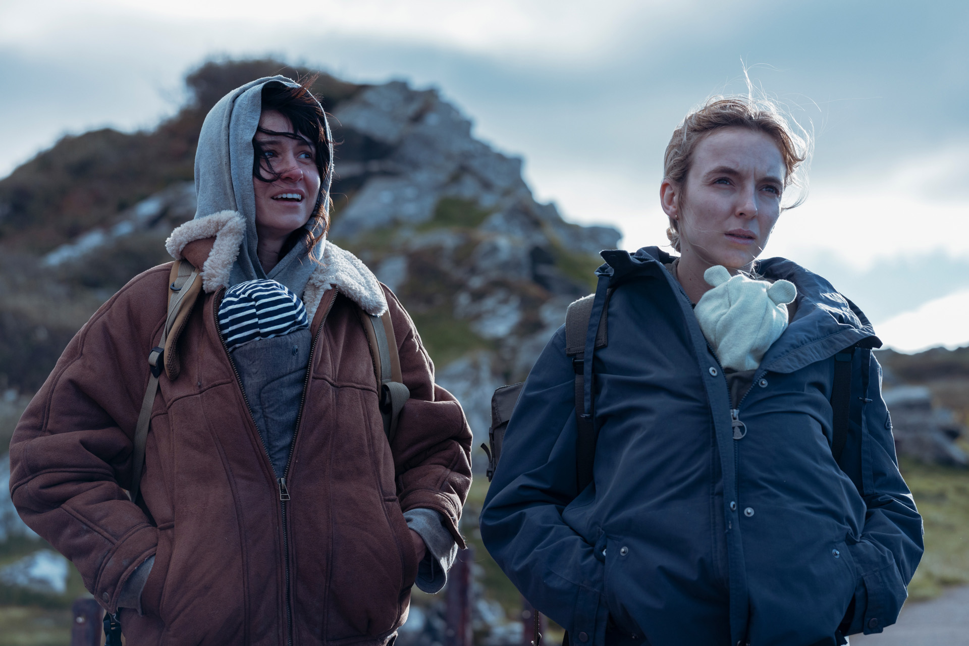 Two women with babies zipped into their coats