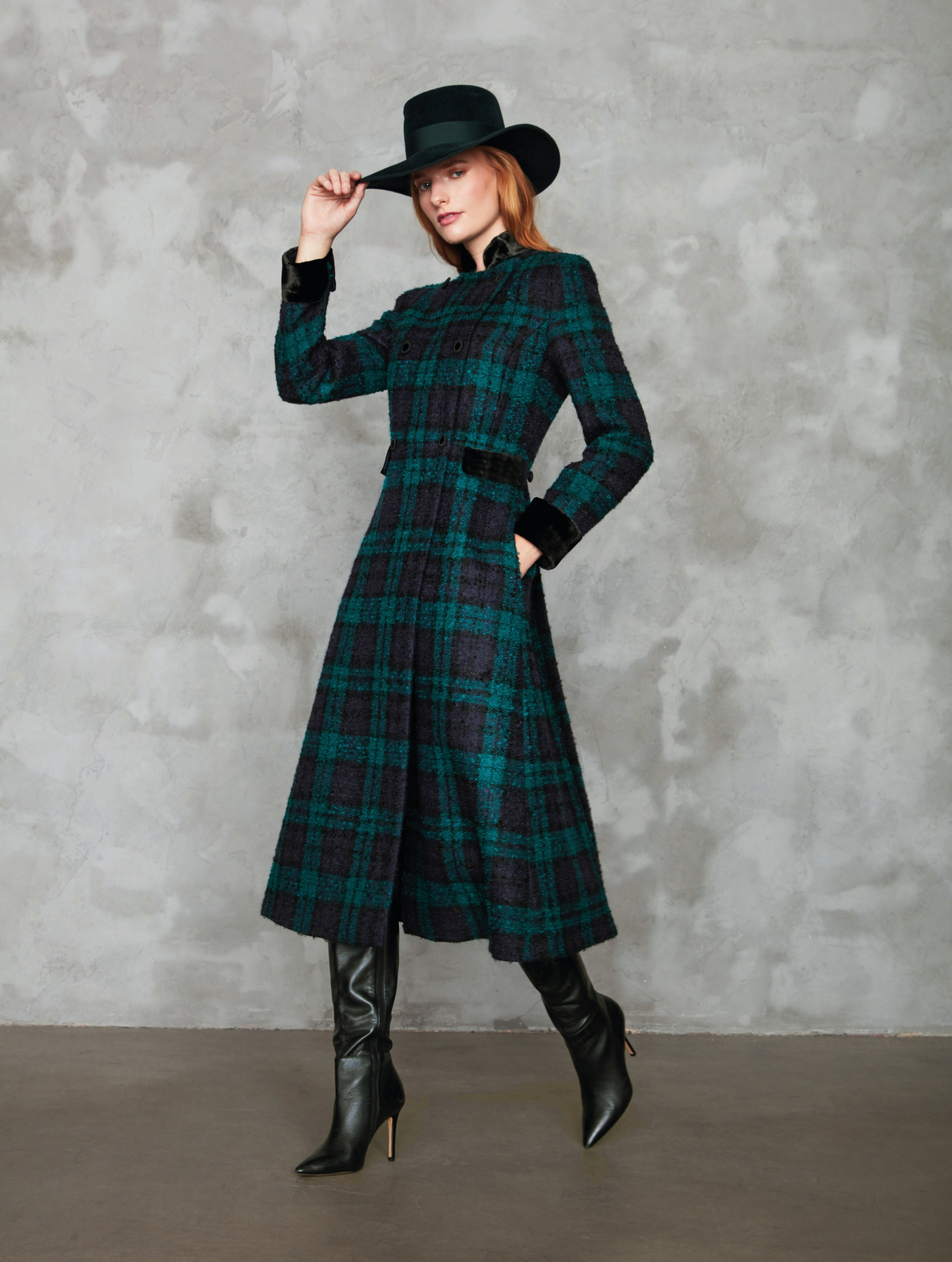 Woman stood in green check coat and black hat