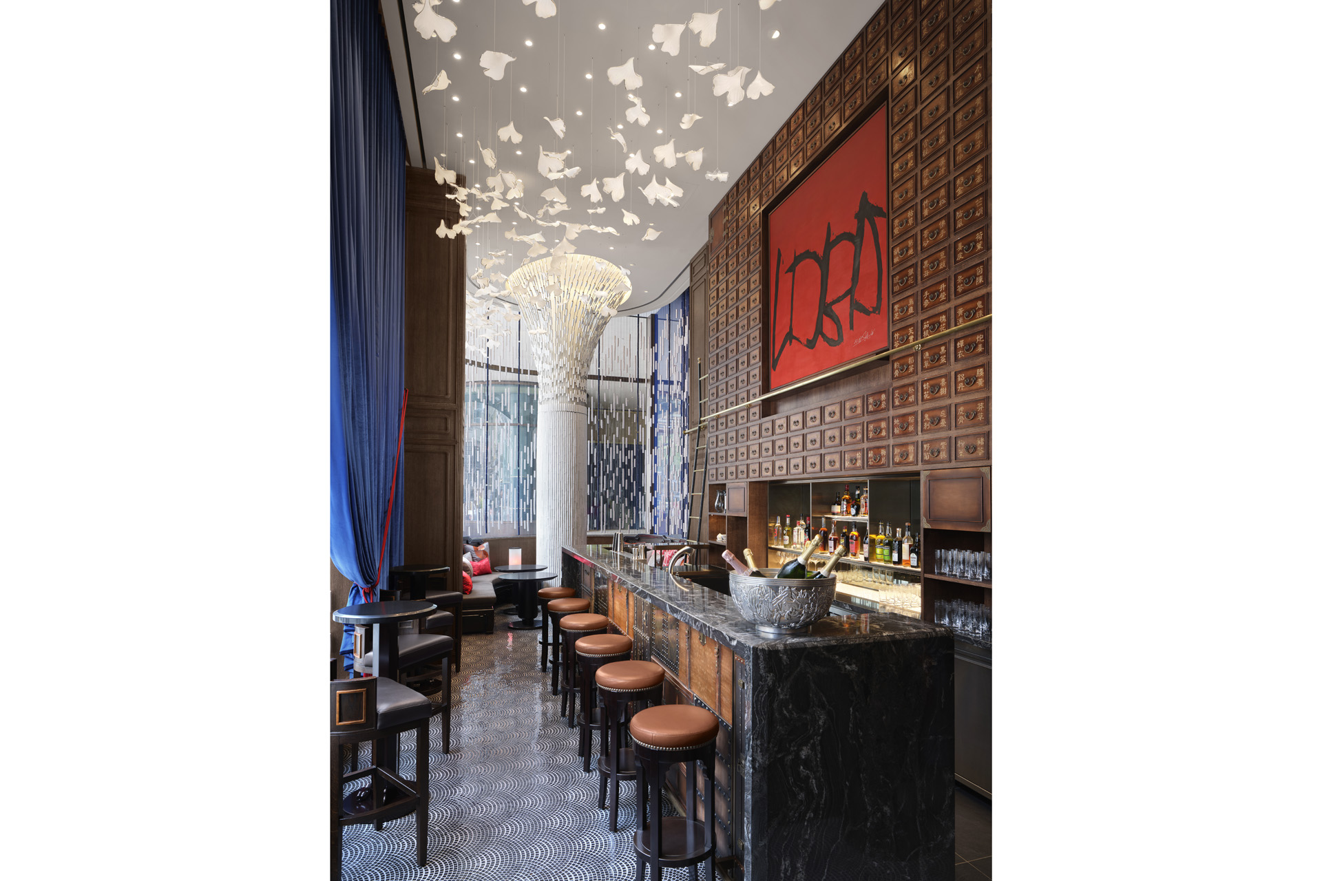 The bar at Little Blue, with stools lined up and a bit white decorated pillar in the centre