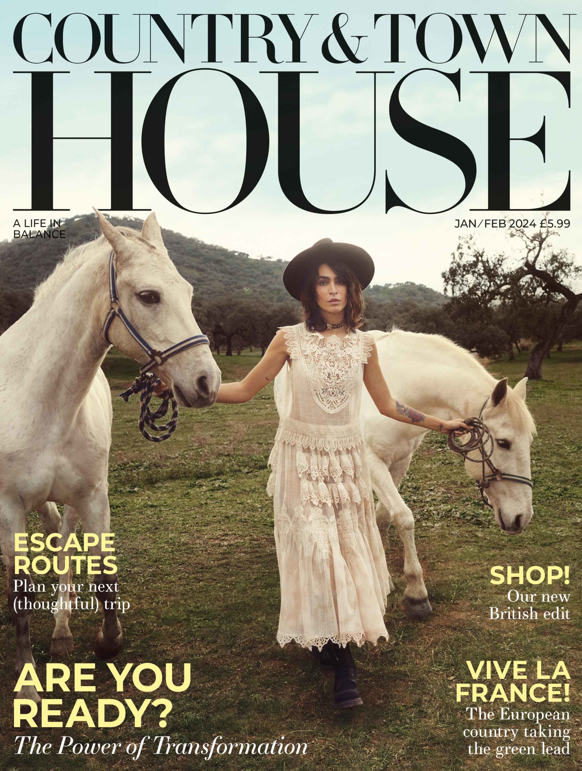 Magazine cover showing model in white boho dress holding two grey horses.