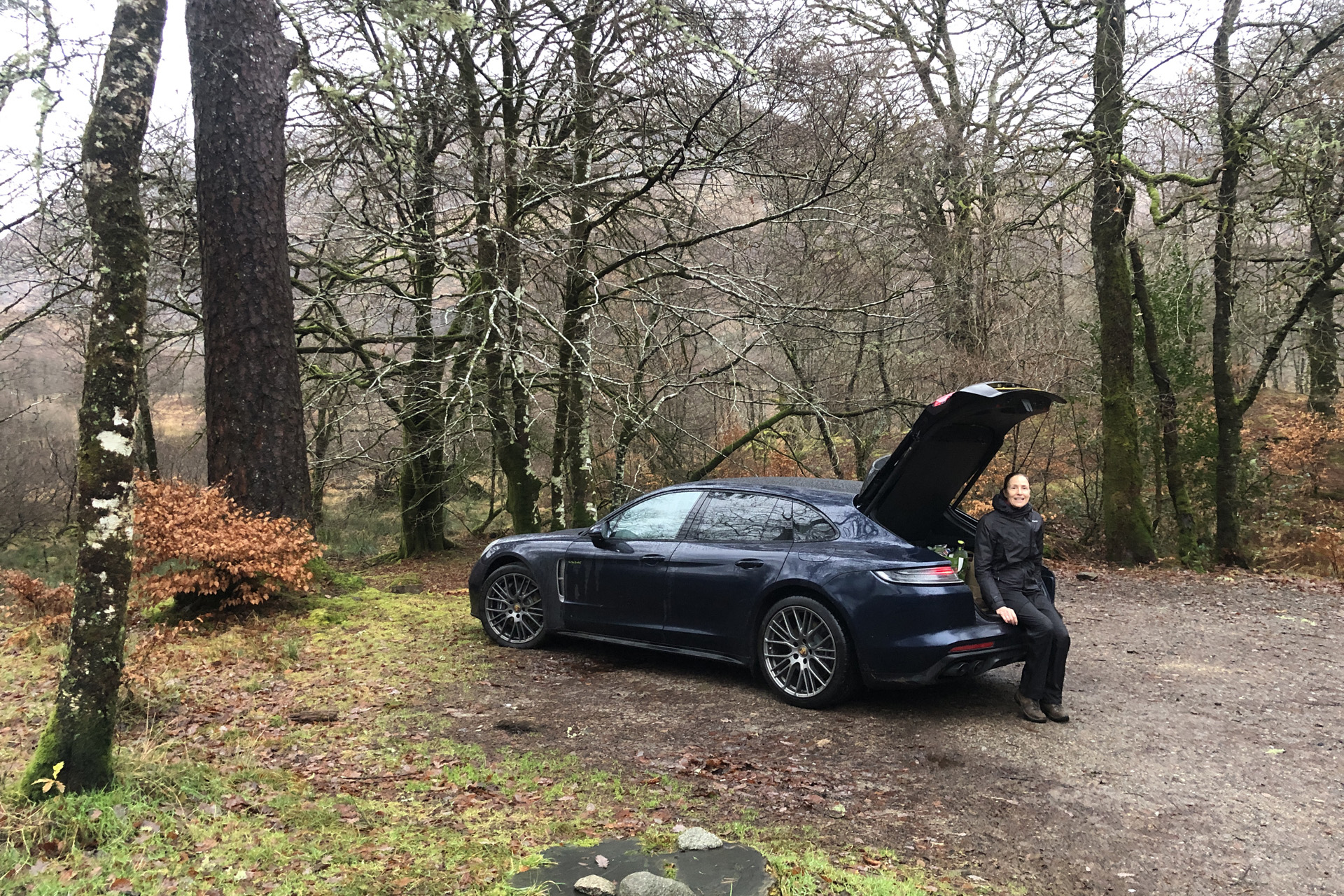 The Porsche Panamera 4 E-Hybrid Sport Turismo Platinum Edition with an open boot in the woods