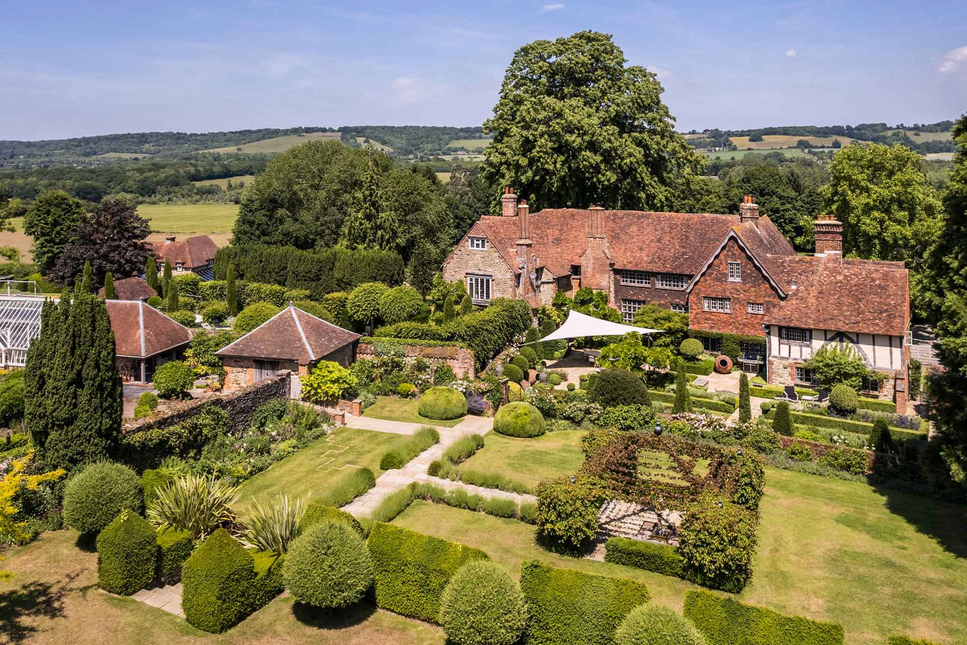 Aerial view of country manor with outhouses and grounds.