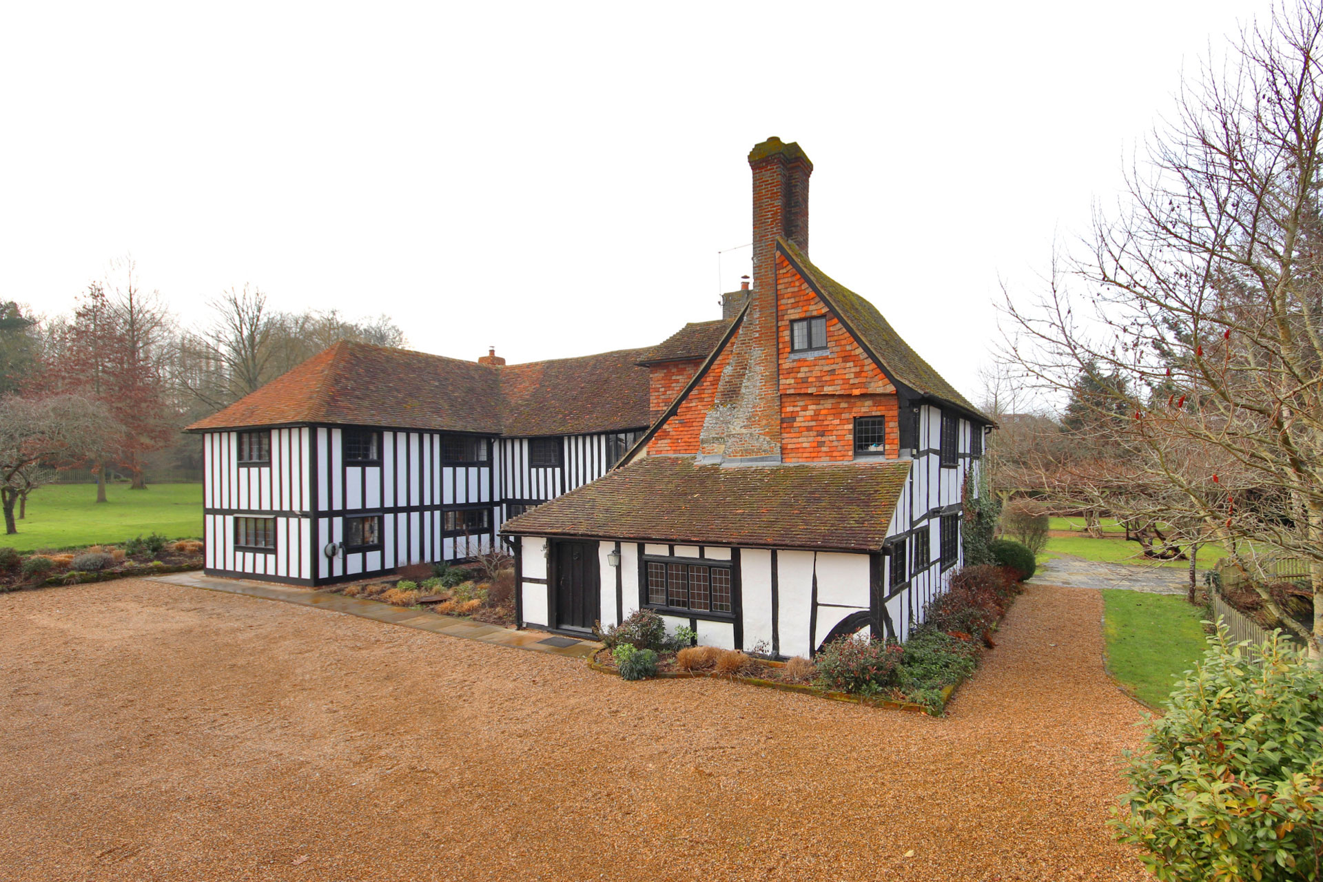 Timbered former farmhouse with brick roof and gravel driveway,