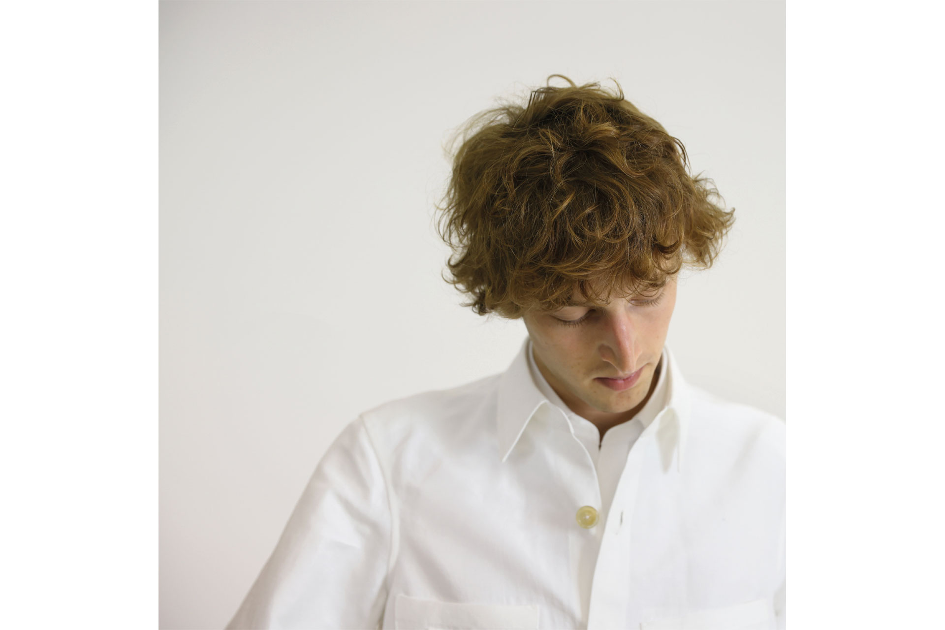 Man wearing white shirt and looking down