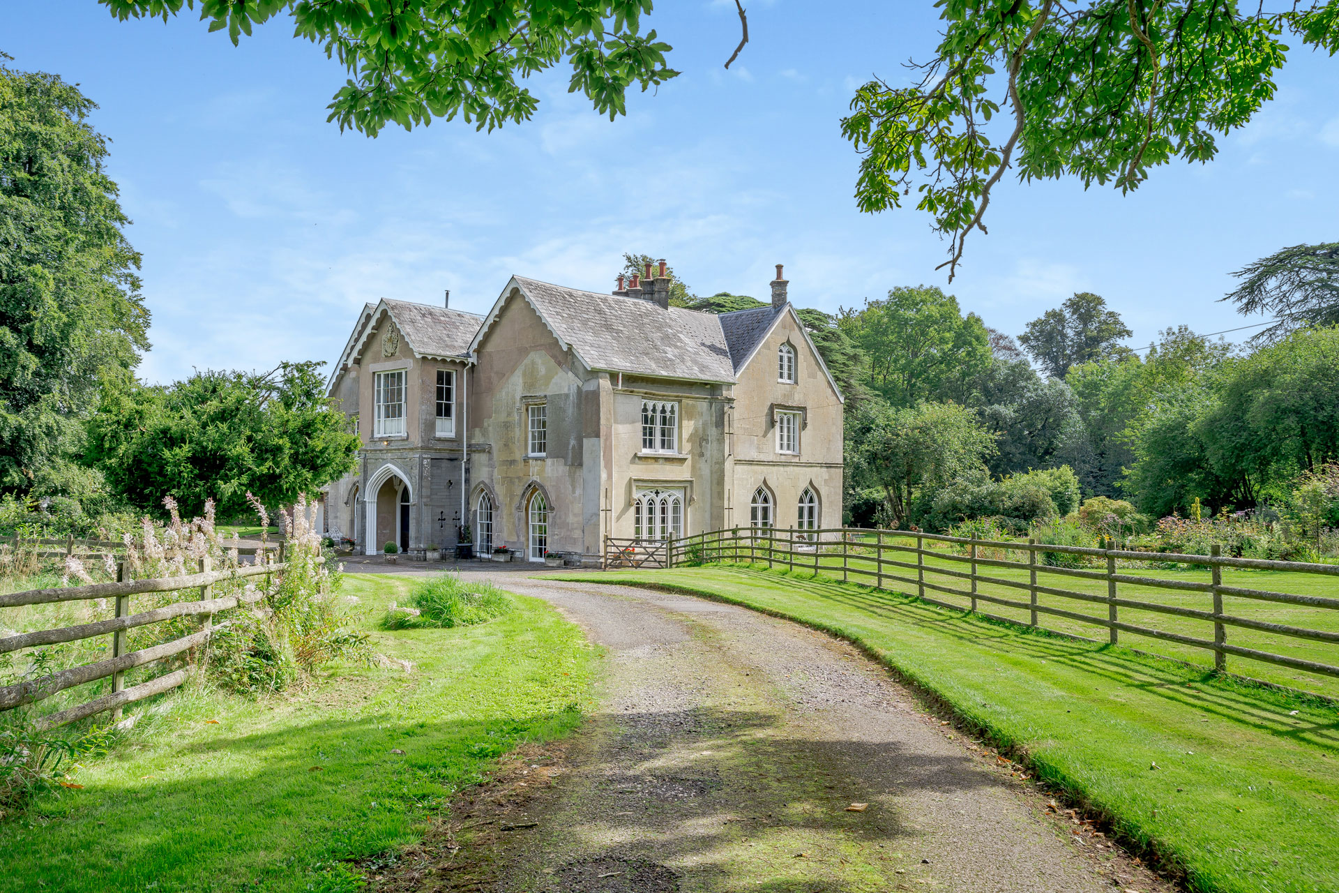 Gothic Georgian manor with driveway and manicured lawns.