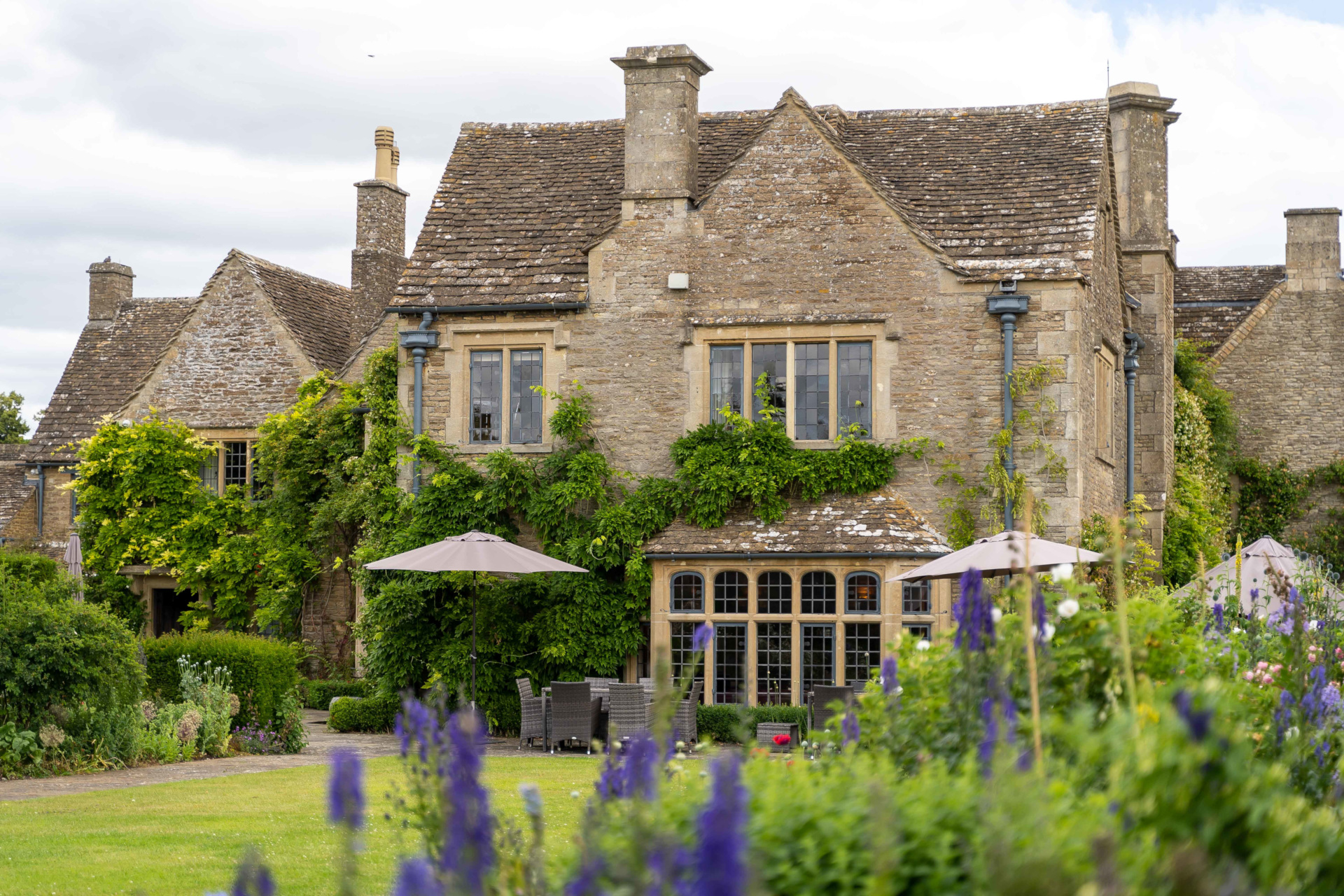 Whatley Manor exterior | Close up of countryside manor with garden and flowers in the foreground