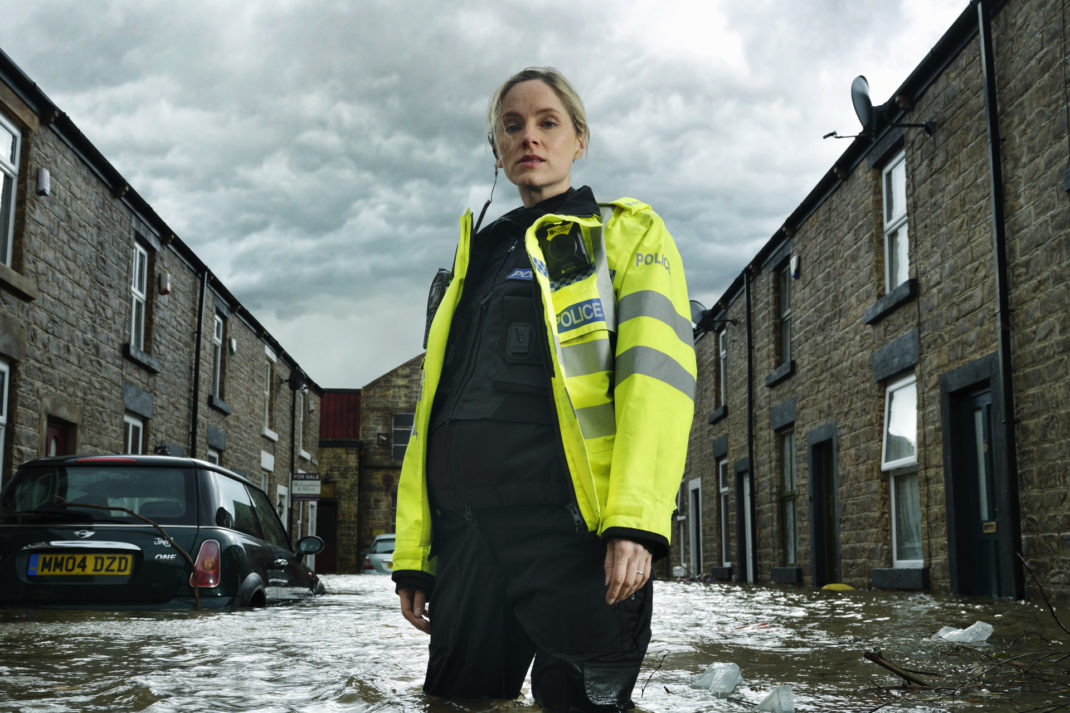 Sophie Rundle stood in flood water