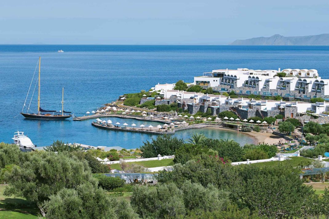 View of waterfront resort, with boats sailing in the bay.