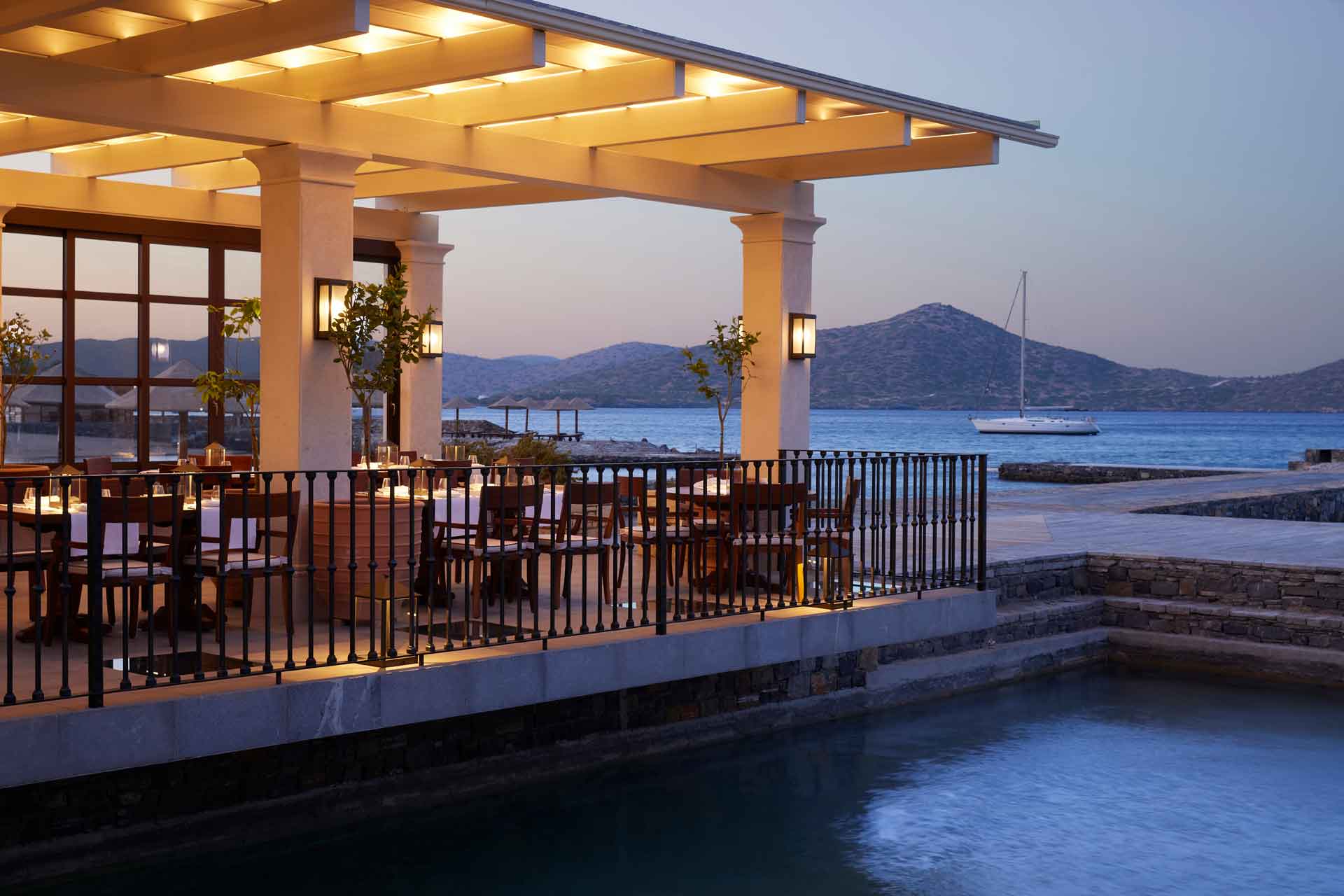 Waterfront restaurant at dusk, with mountains in the distance.