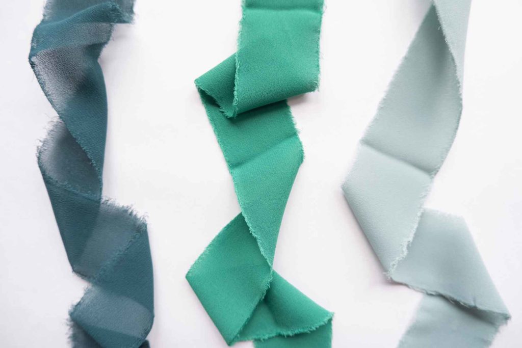 Dark blue, seafoam green and pale blue ribbons on a white background.