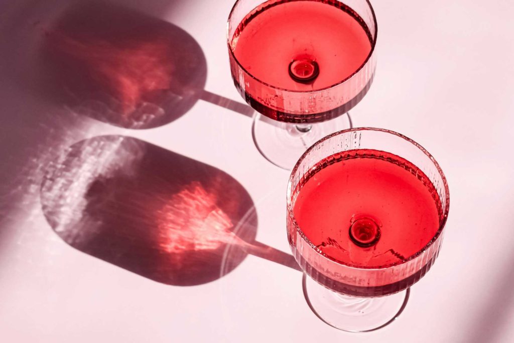 coupe cocktail glasses with red drinks in