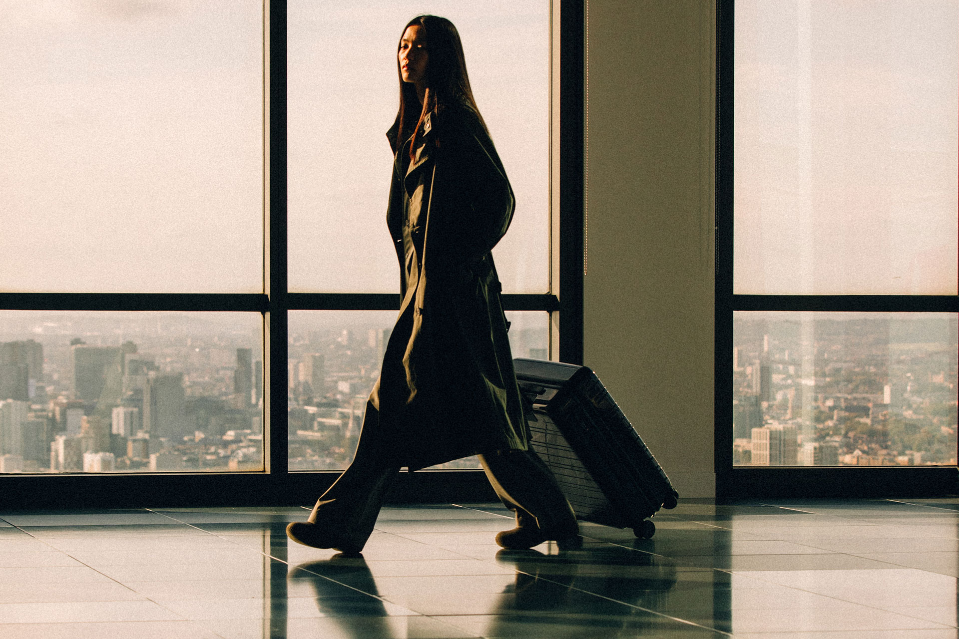 Woman in airport with hard-shell suitcase