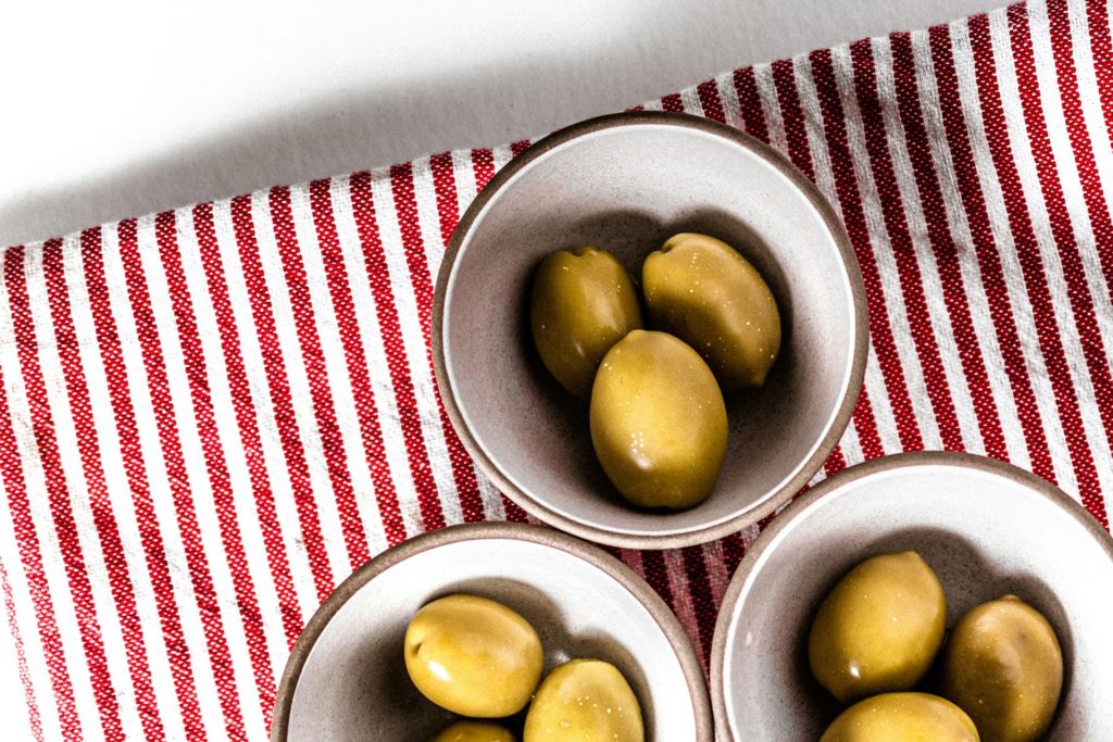 Three bowls of olives on a red striped background