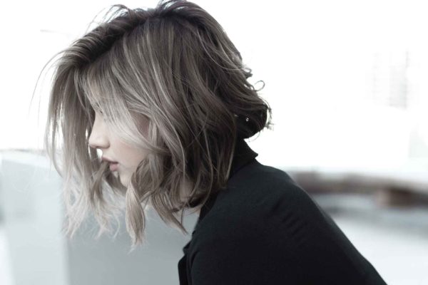 Side profile of woman with short, dark hair and blonde highlights