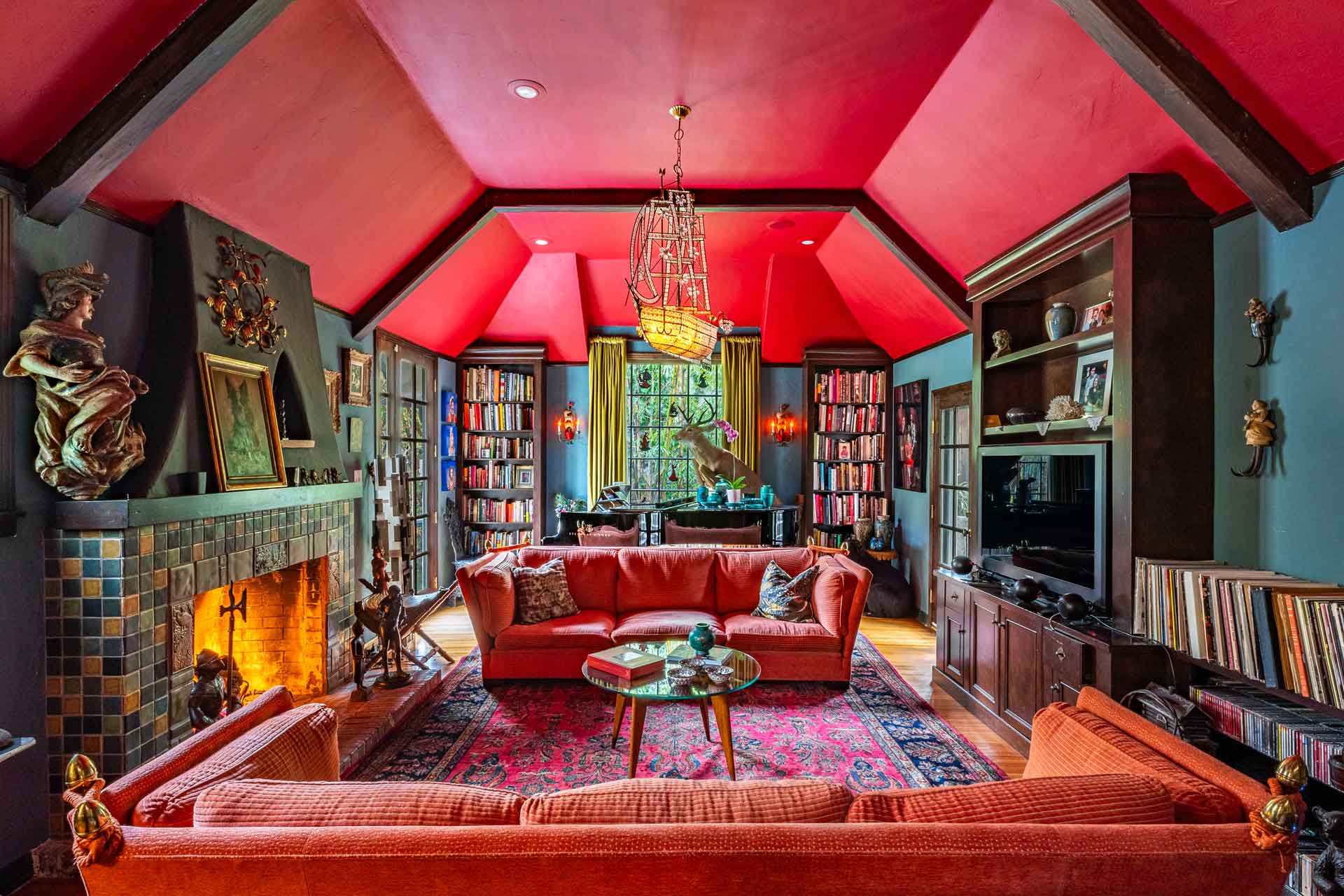 Living room with red walls, a fireplace, and a vaulted ceiling.