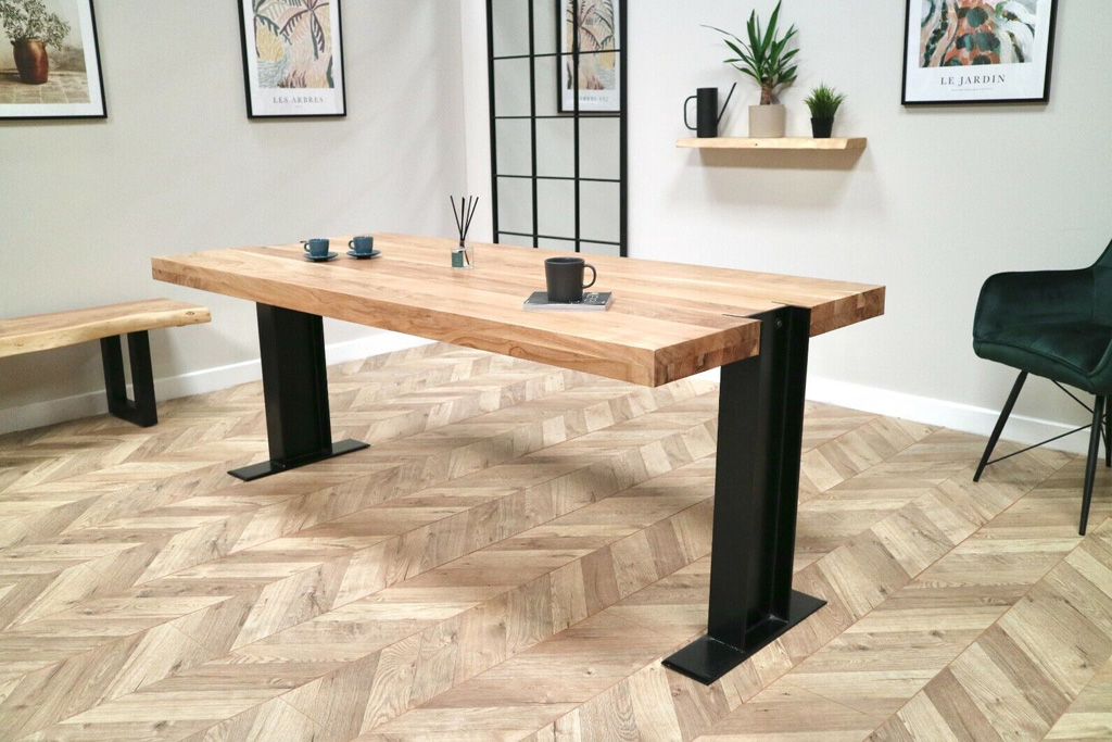 A thick wooden dining table with black metal industrial legs