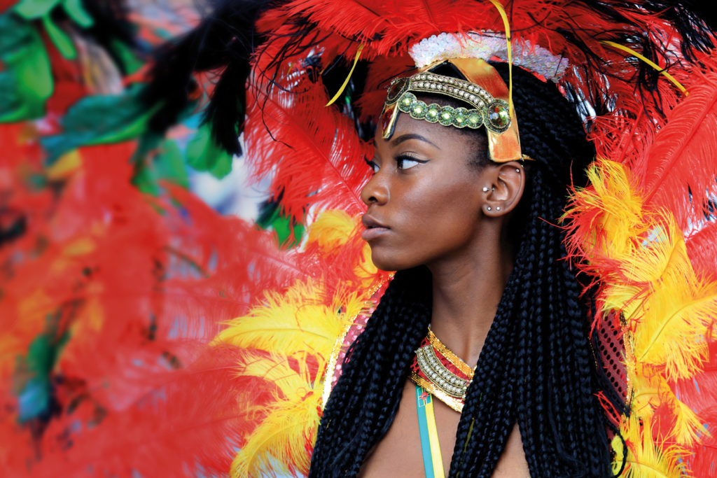 A black woman wearing a colourful feather head dress