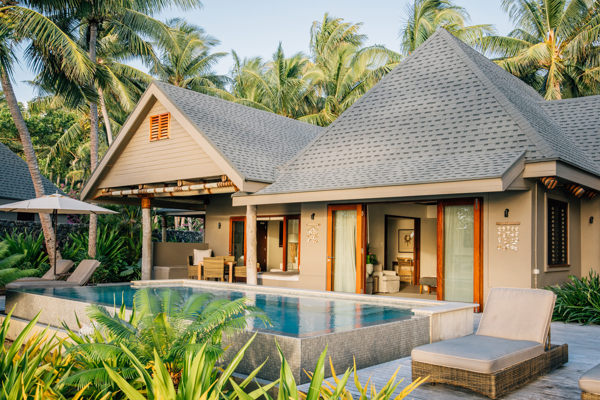 A beach villa with a pool and plants