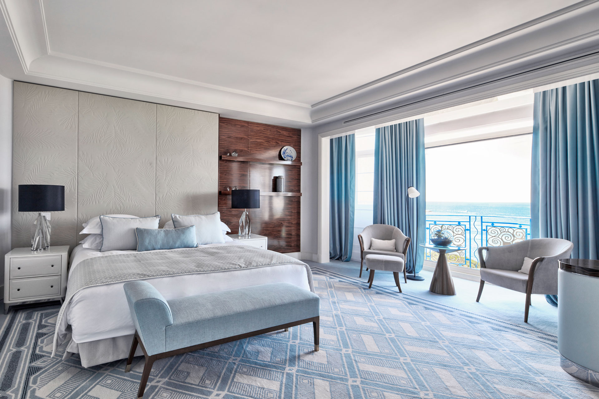 Penthouse bedroom at Hotel Martinez, featuring pale blue carpets and curtains, a blue velvet chaise longue, and white furniture.