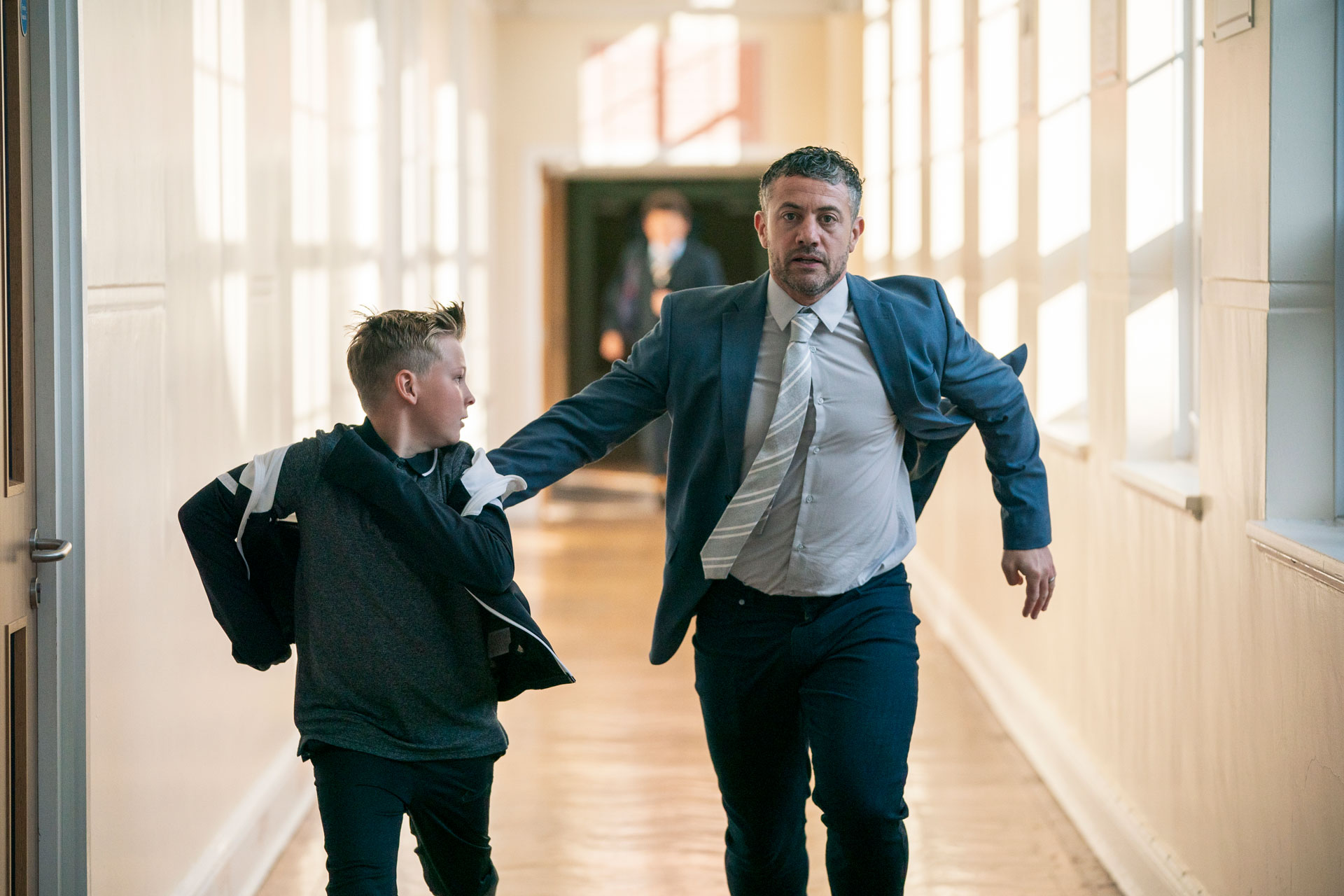 Student and teacher running down a school corridor in The Gathering