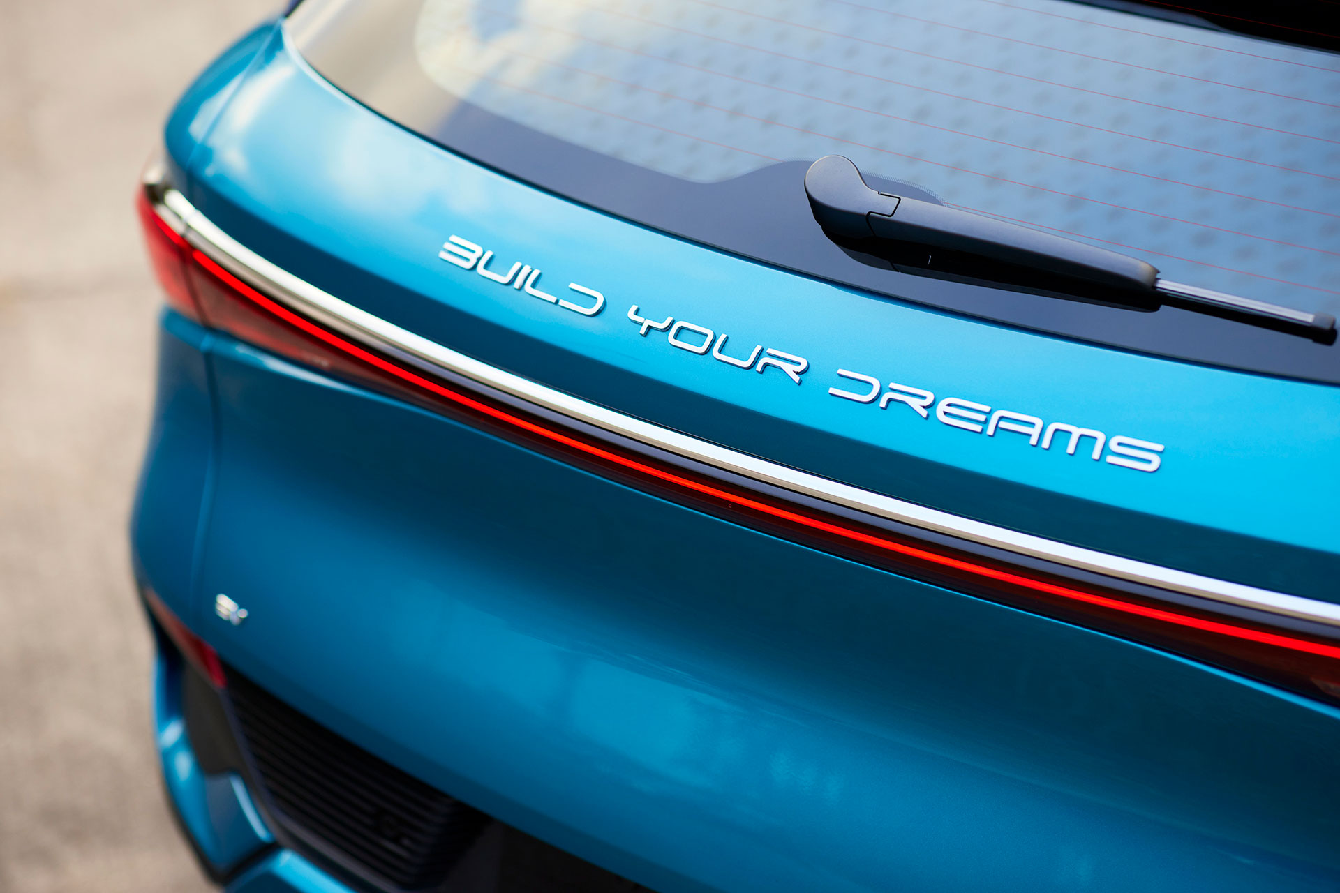 'Build Your Dreams' logo on the boot of a blue BYD Atto 3.