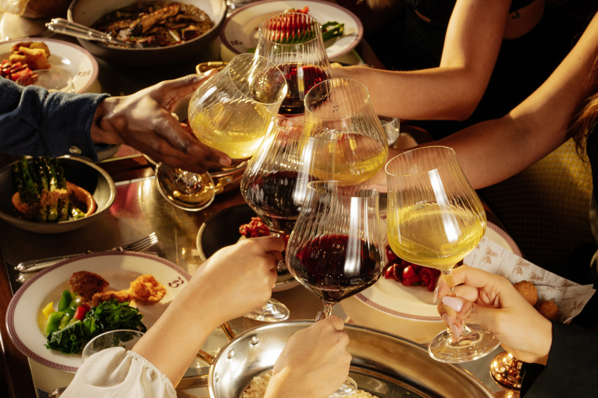 People toasting wine glasses over set table