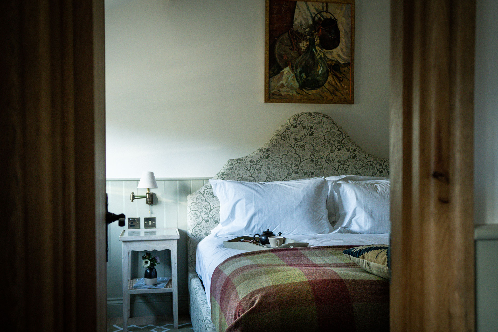 Cottage bedroom with colourful wool quilt and white bedding.