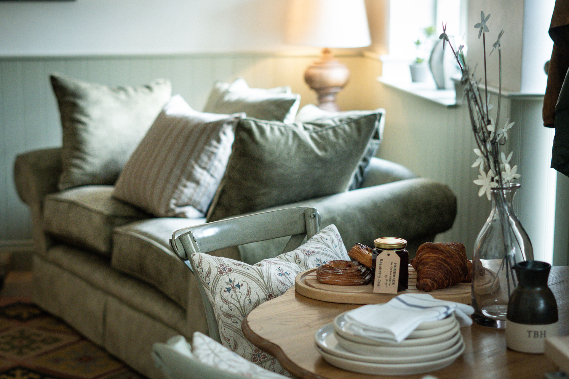 Cottage living room with grey sofa and fresh pastries on the table beside.