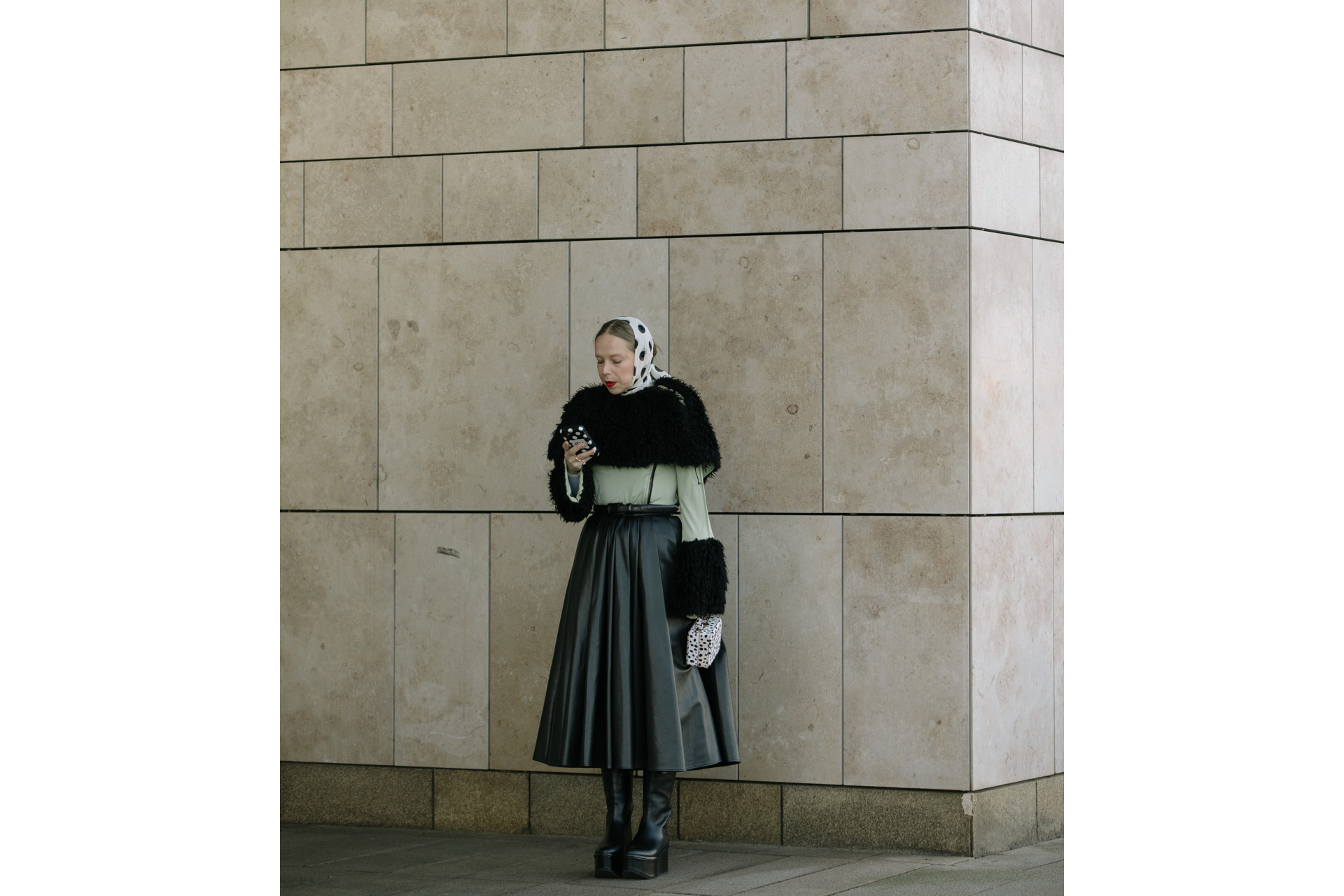 Woman in black and white outfit leaning against wall