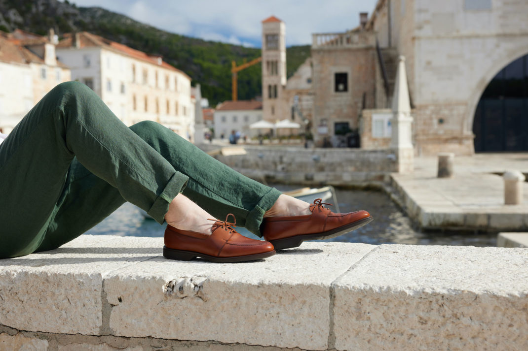 Crockett & Jones model wearing leather boat shoes sitting on wall british luxury news february 2024