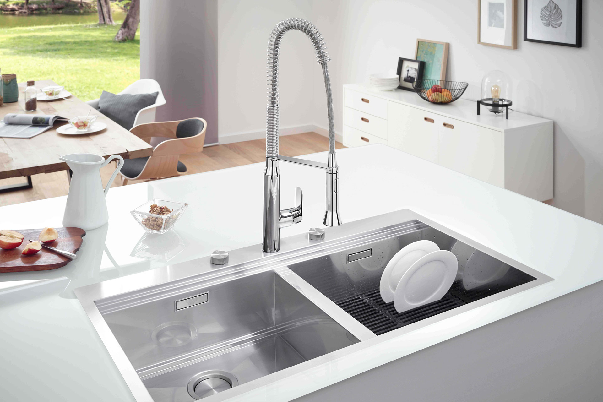 White kitchen island with integrated stainless steel sink and flexible tap.