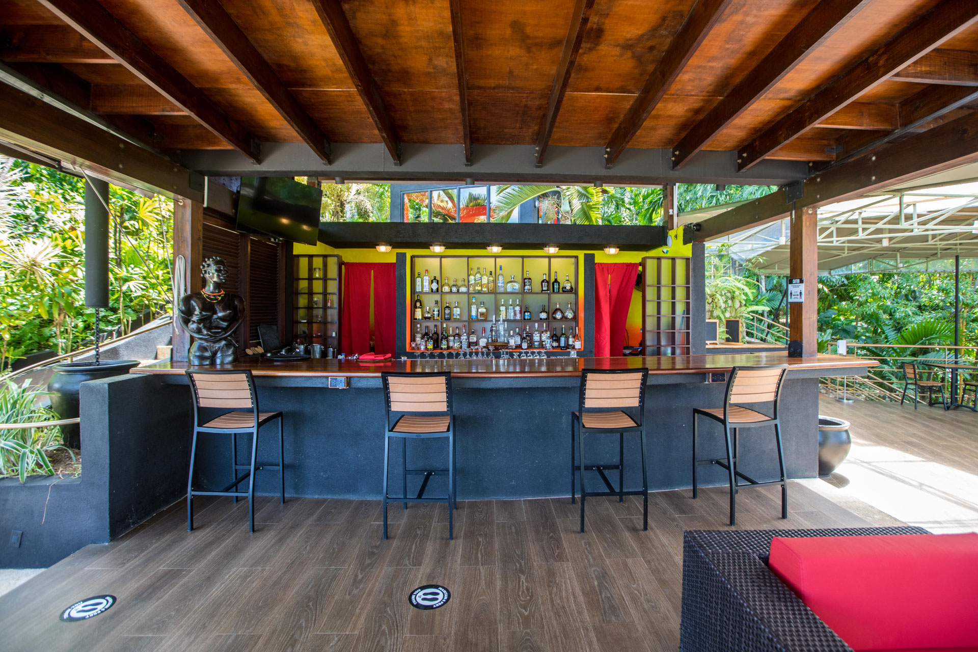 Outdoor bar with wooden beams and rainforest views.