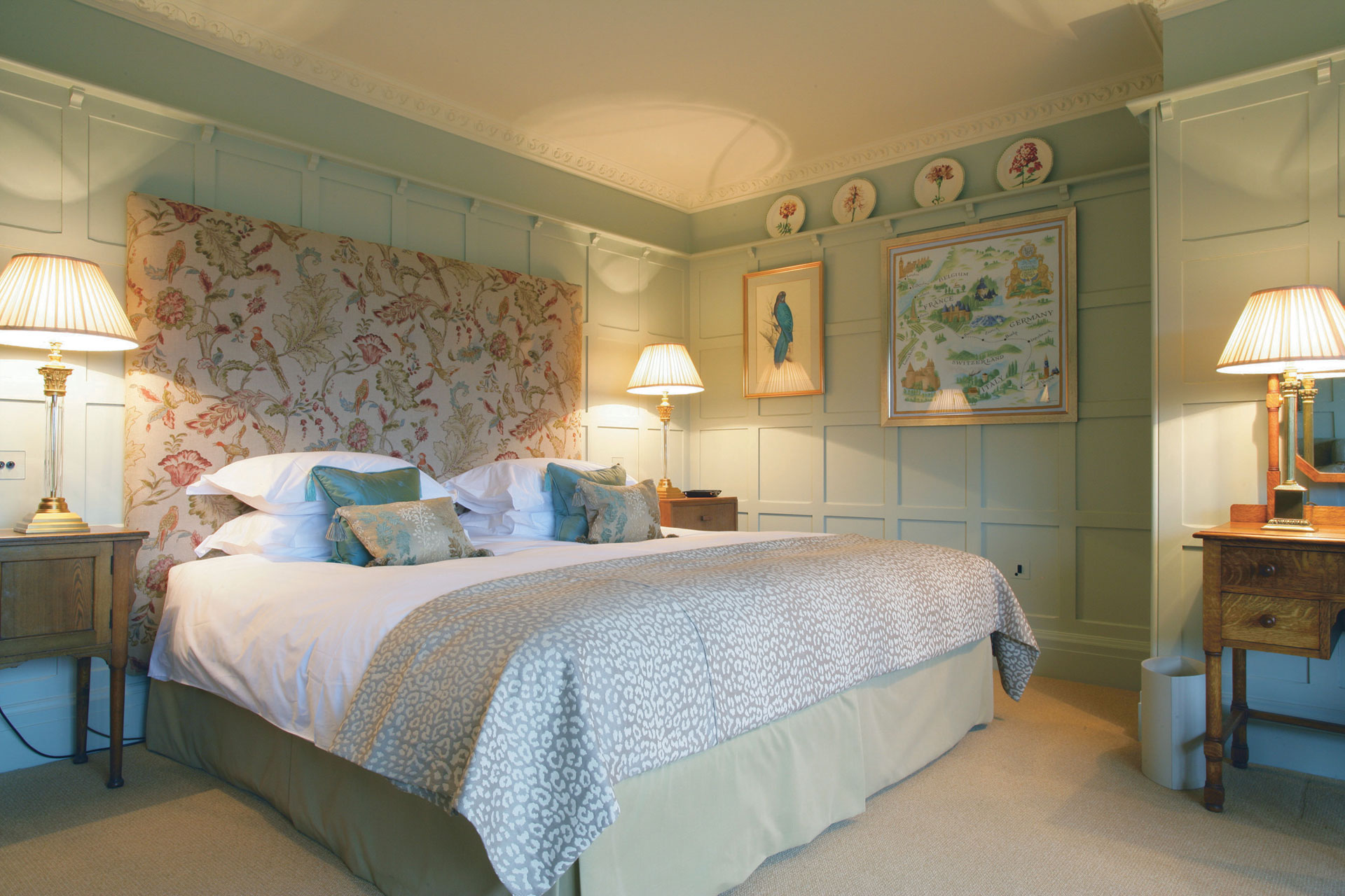 Bedroom with mint green panelled walls and a floral headboard.