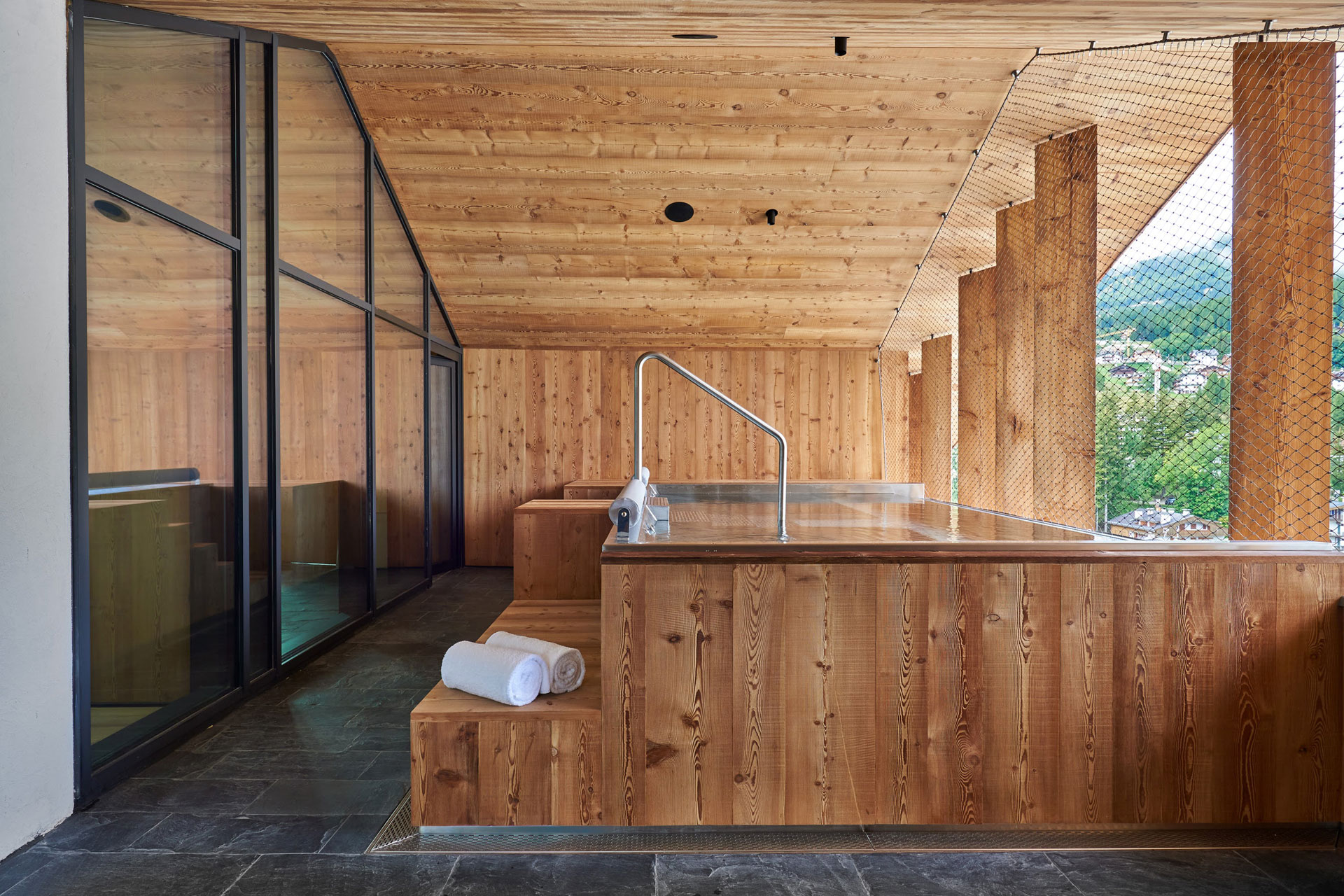 Wood-panelled jacuzzi with a view of the Dolomites.
