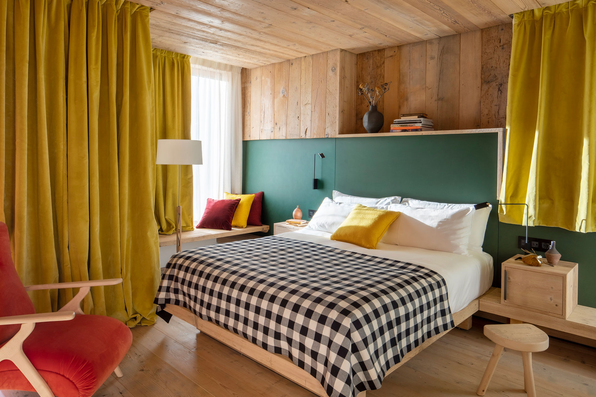 Alpine bedroom with mustard yellow curtains, a gingham throw and yellow cushions on the bed