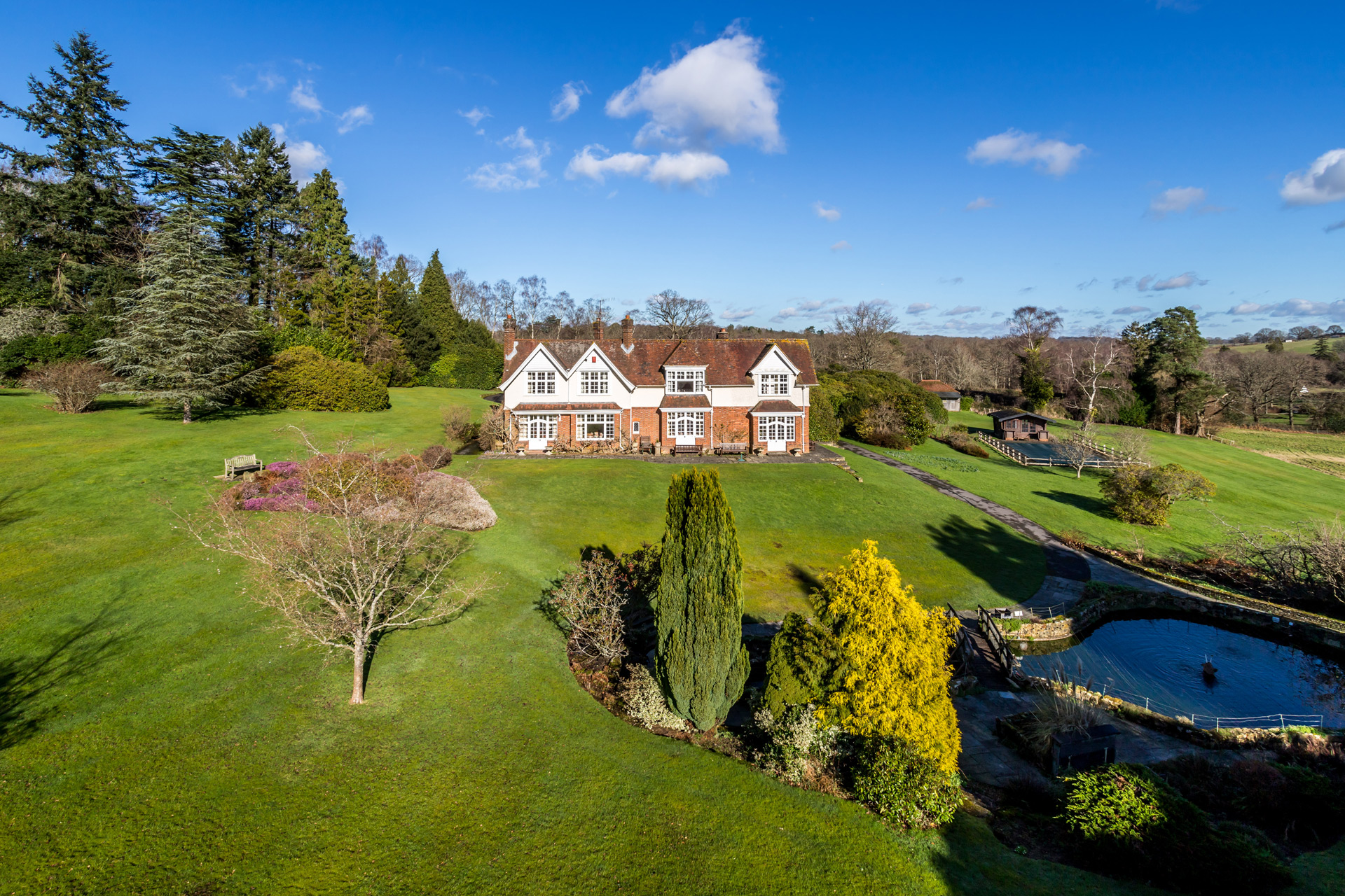 Aerial view of country house with grounds and a pond.