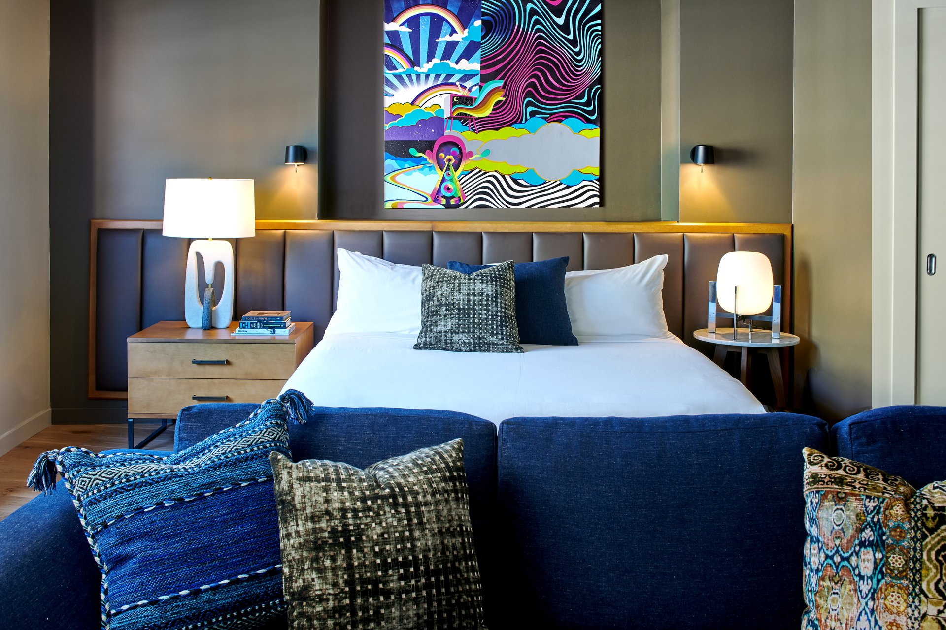Bedroom with blue sofa and colourful wall art