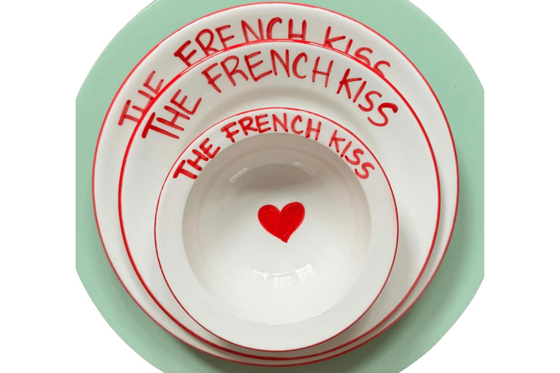 Set of plates with 'The French kiss' painted in red on the rim and a heart in the middle.