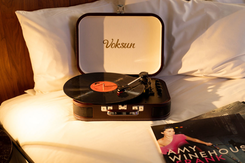 Record player on hotel bed with Amy Winehouse's 'Frank' vinyl beside it..