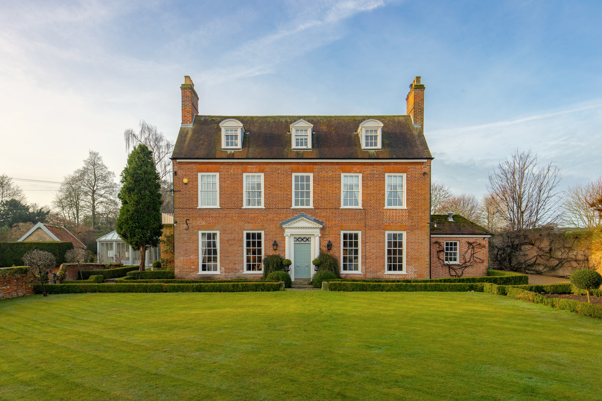 Large red brick country manor with a lawn in front.