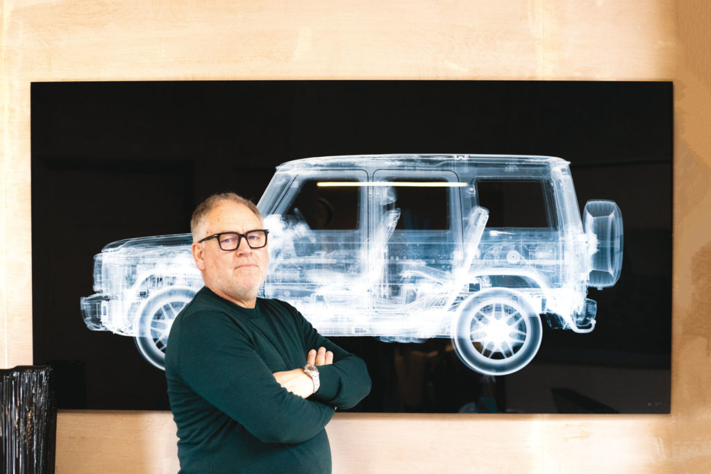 Artist Nick Veasey standing in front of one of his pieces, an X ray of a car.