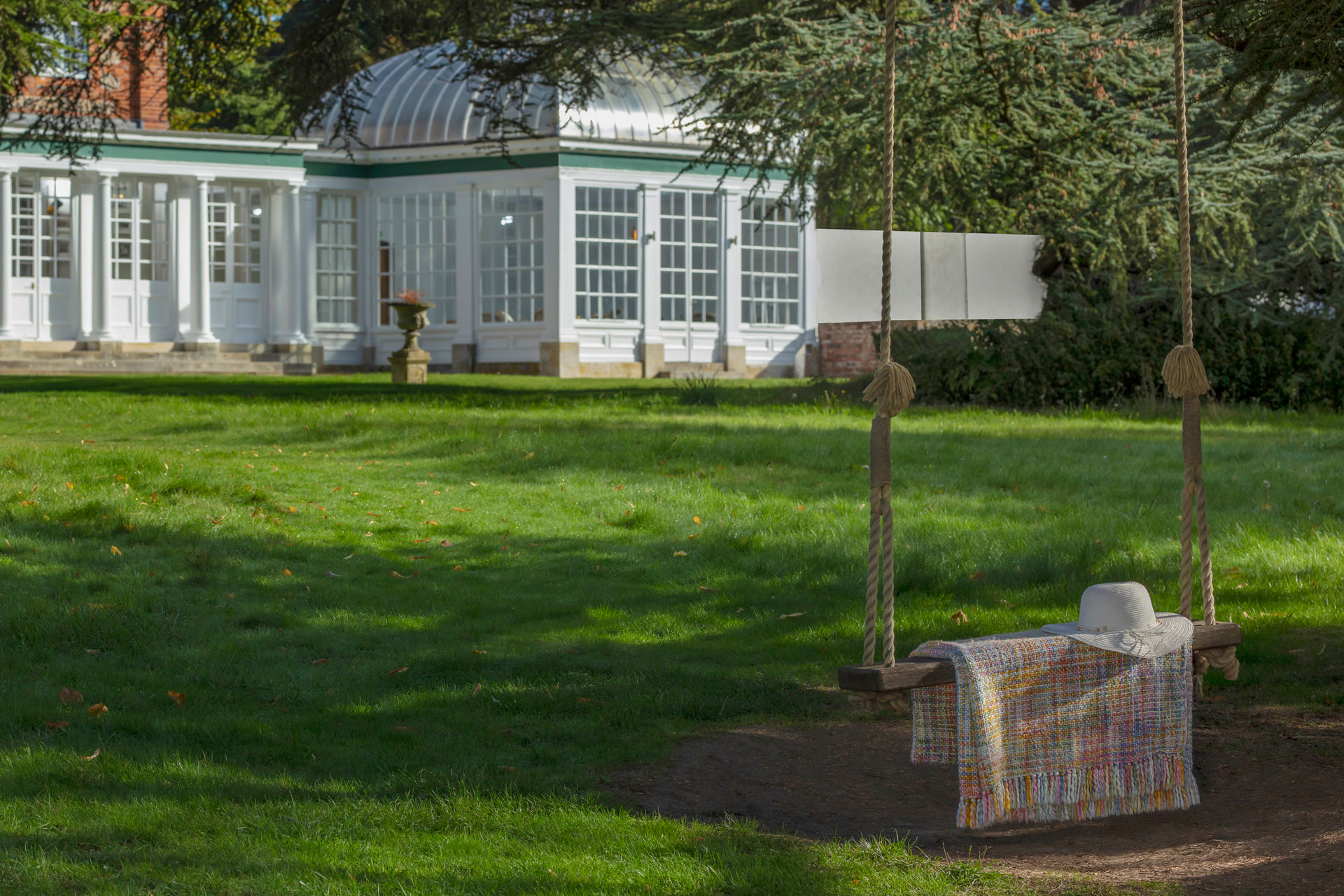 Exterior of Norton Park Hotel, with a lawn and a swinging bench.