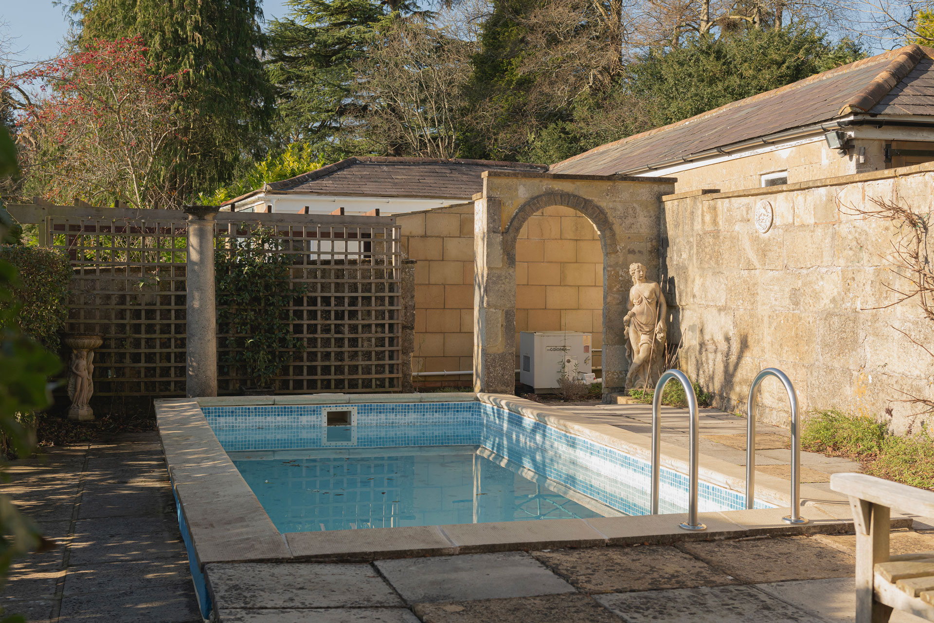 Heated outdoor swimming pool with stone wall beside it