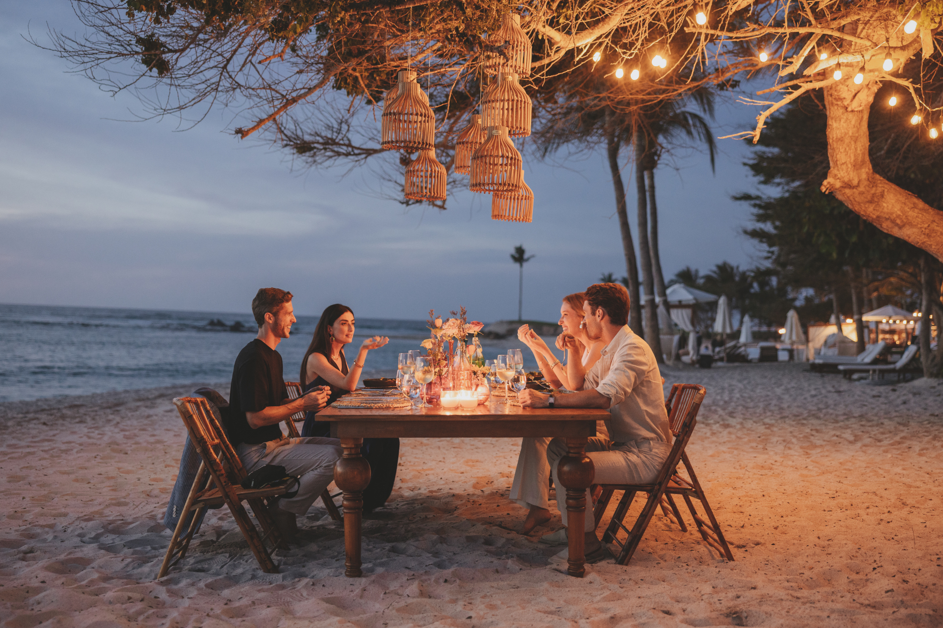 People sat at dining table on beach at sunset