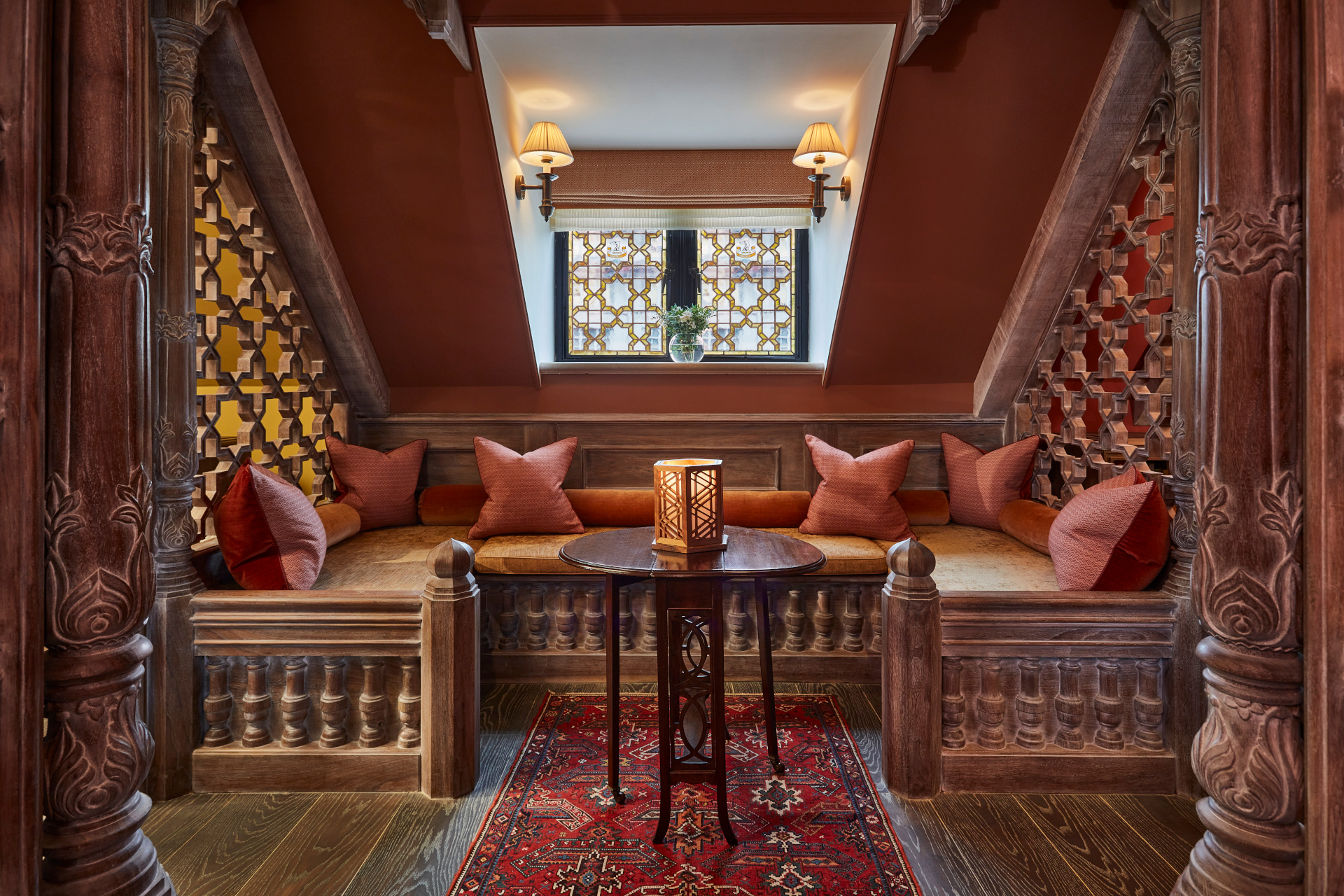 Red seating area with gold and red cushions, wooden finishes and red ceiling with stained glass window