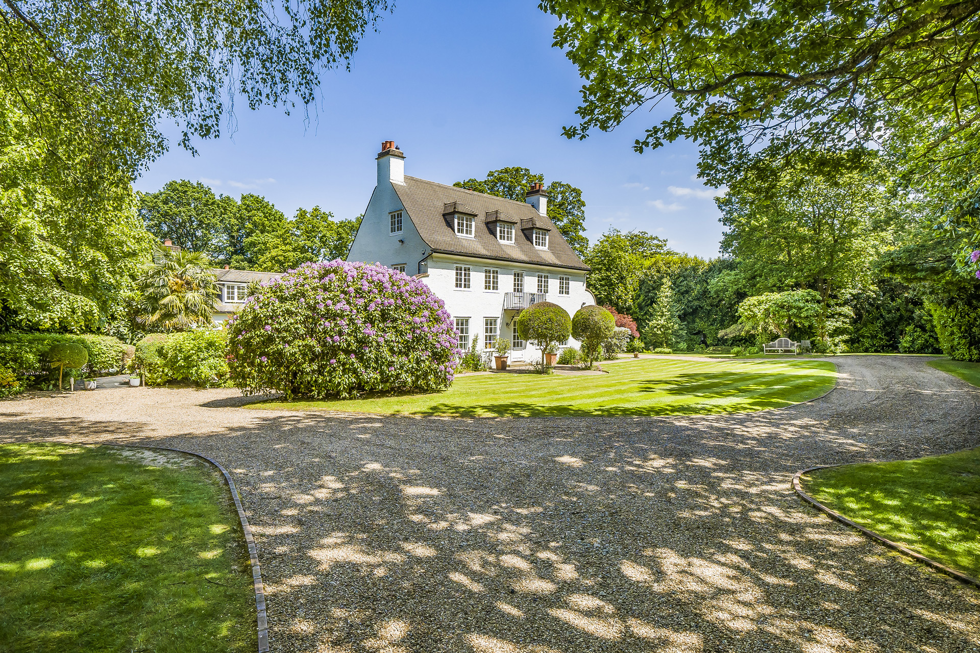 Country home with a large gravel driveway and a slate roof.