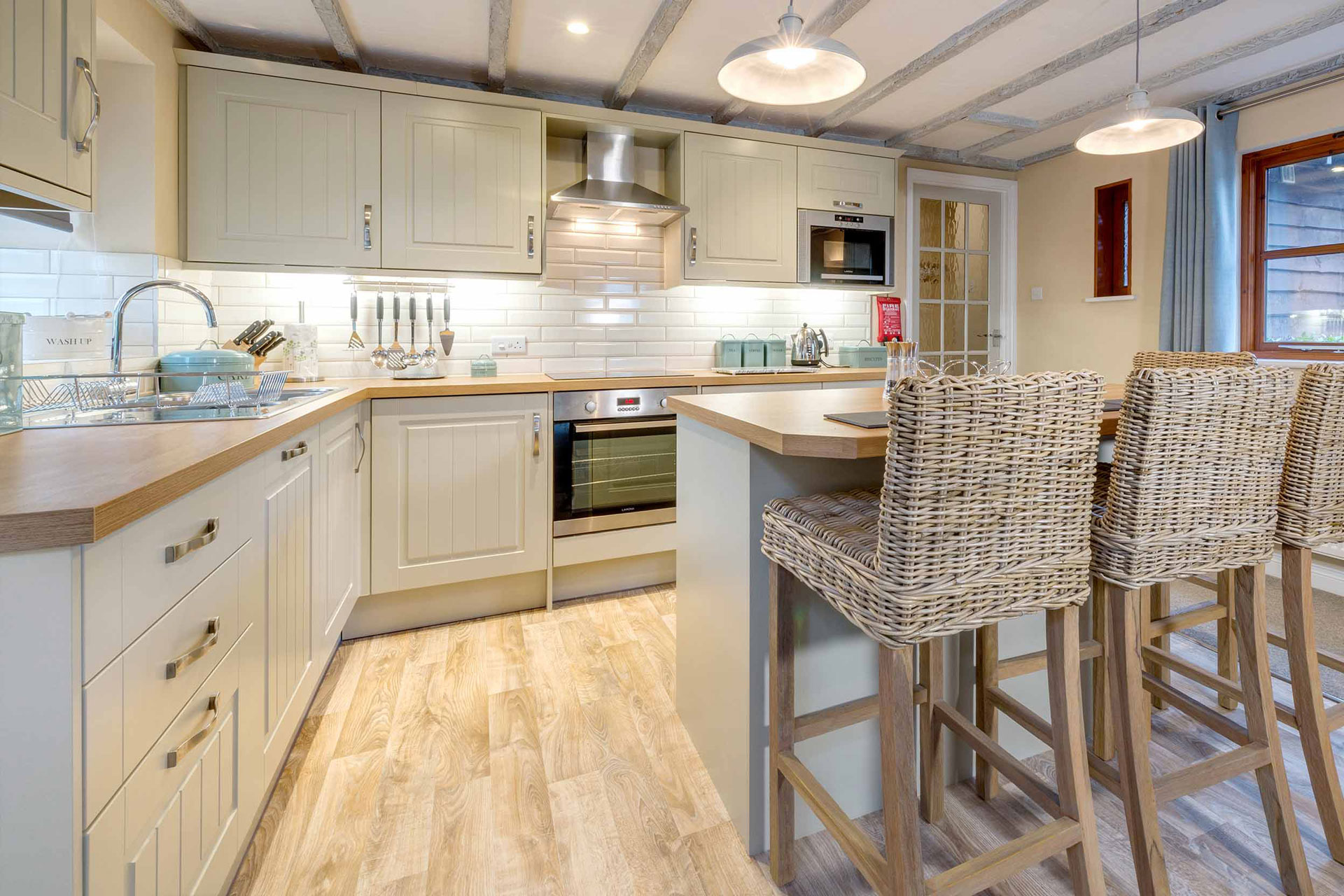 Shaker style kitchen with white cabinets and wicker bar chairs.
