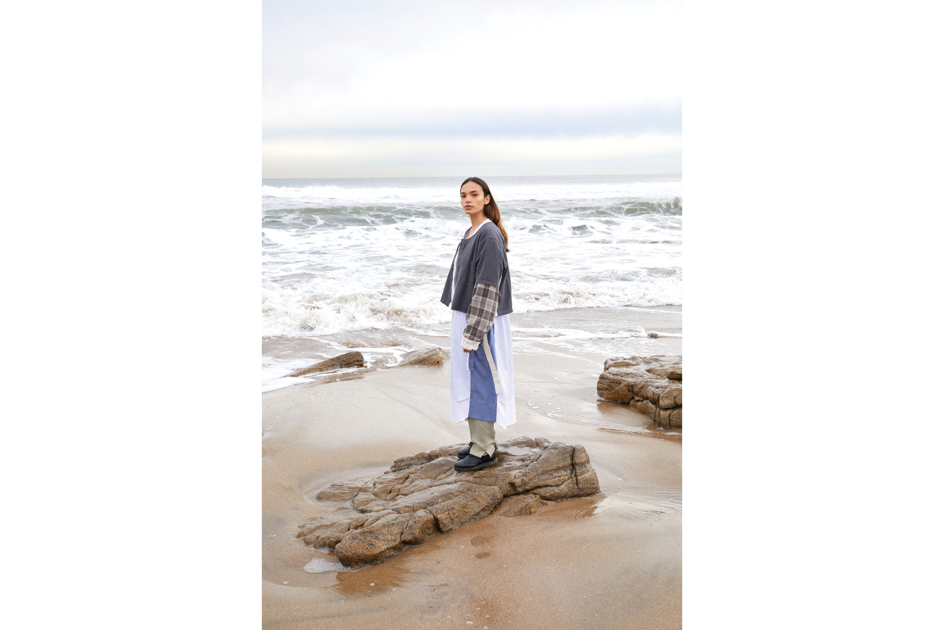 Woman stood on rock on beach