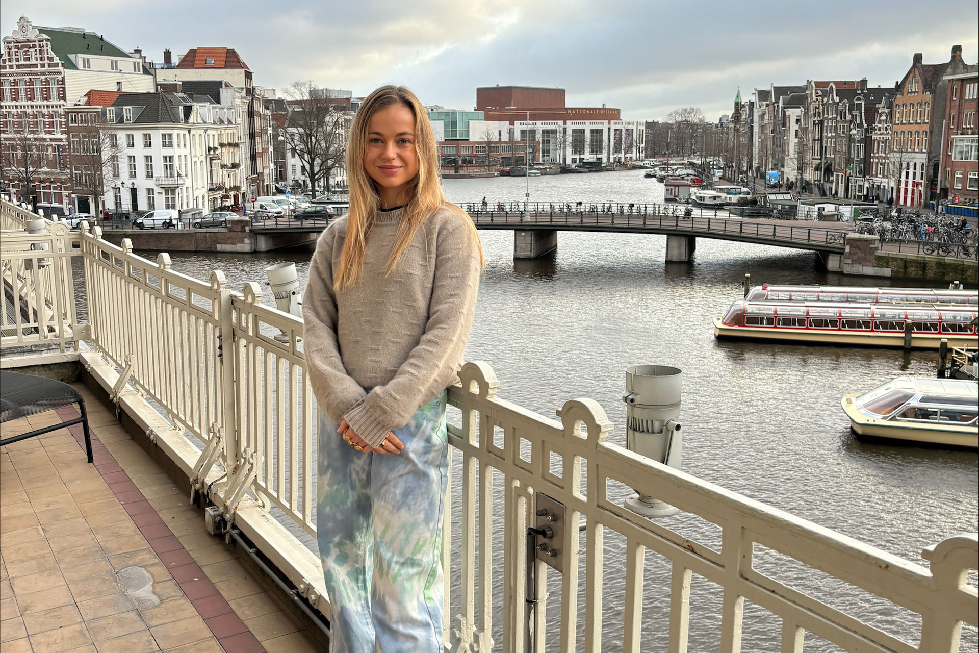Amelia Windsor on a bridge in Amsterdam, with canals in the background.